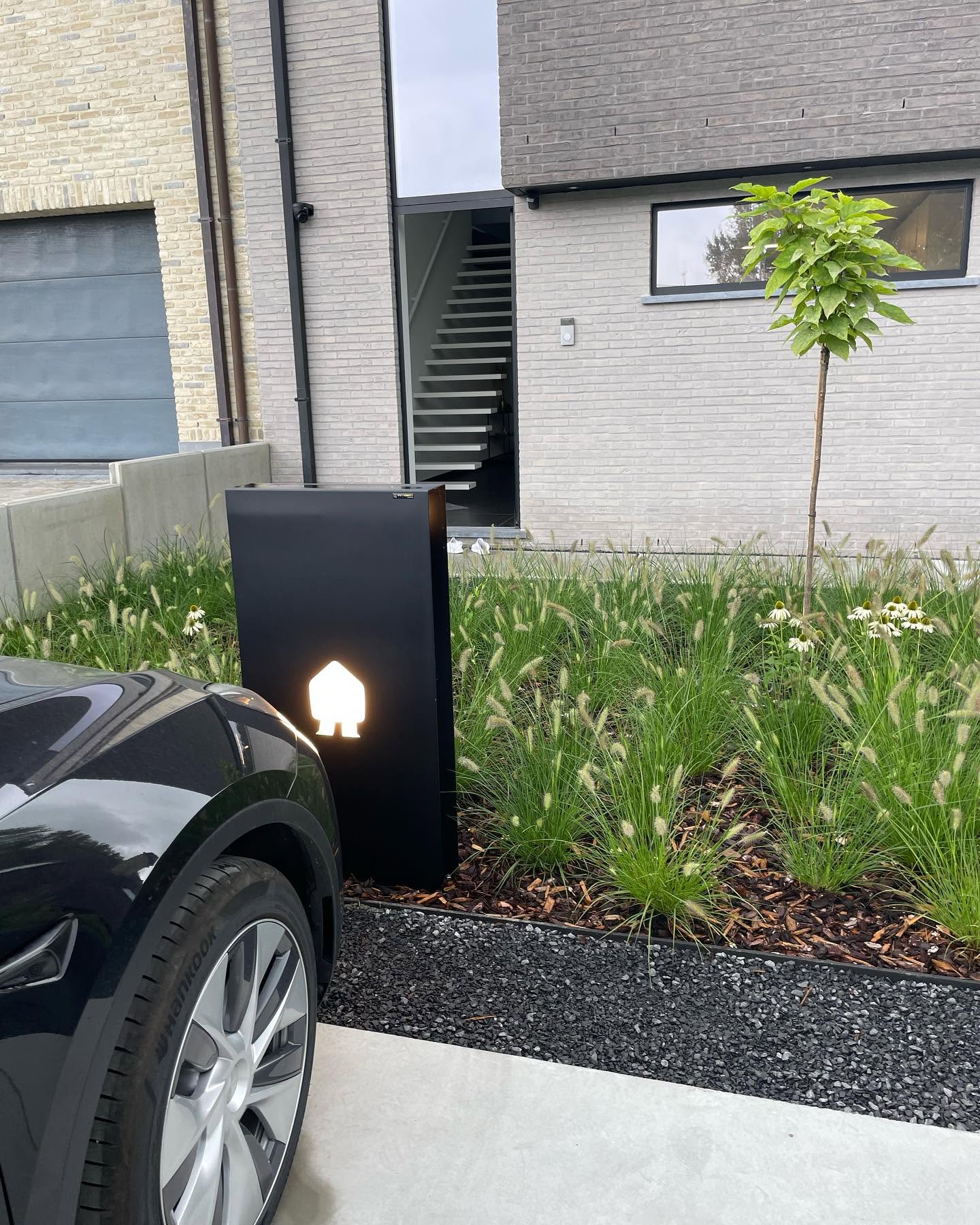 Snellader naast Tesla in tuinpad